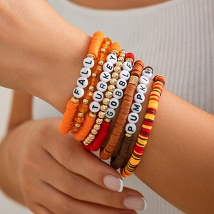 Close-up of bohemian beaded bracelet set with Fall theme charms and warm orange tones