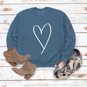 Flat lay of blue crewneck sweatshirt with heart print and stylish accessories