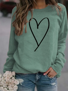 Detail of green crewneck sweatshirt with minimalist black heart print on casual fabric