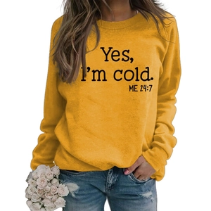 Detail of yellow sweatshirt featuring black Yes I'm Cold slogan print and soft cotton fabric