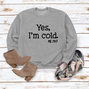 Close-up of gray 'Yes, I'm cold' sweatshirt styled with winter boots and a scarf