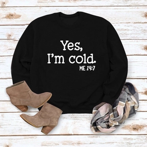 Flat lay of black 'Yes I'm Cold' sweatshirt paired with brown boots and plaid scarf