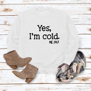 Flat lay of white sweatshirt with 'Yes I'm Cold' print and stylish autumn accessories