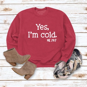 Detail of red crewneck sweatshirt featuring Yes I'm Cold print with stylish winter accessories
