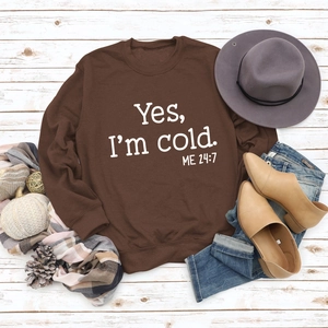 Flat lay of brown cotton sweatshirt with Yes I'm cold print on rustic wood background