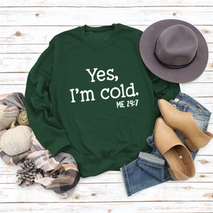 Close-up of Yes I'm Cold print on green sweatshirt styled with autumn accessories