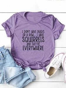 T-shirt viola in cotone con scritta divertente e dettaglio nodo su fondo di legno