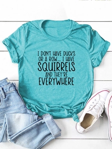 Dettaglio di una t-shirt turchese con stampa scritta e un nodo elegante sull'orlo frontale