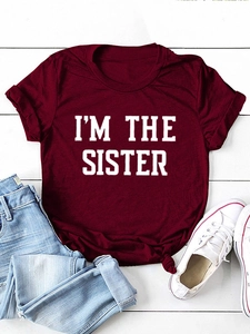 T-shirt bordeaux en coton avec imprimé I'M THE SISTER posé sur un fond en bois blanc