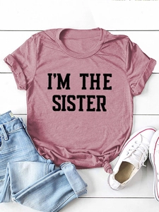 Détail de l'imprimé I'M THE SISTER sur un t-shirt en coton rose avec nœud latéral