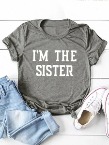 Détail d'un t-shirt gris avec imprimé I'M THE SISTER et nœud élégant à l'avant