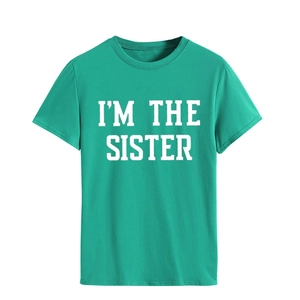 Gros plan sur l'imprimé I'M THE SISTER sur un t-shirt vert en coton col rond
