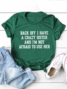 Forest green cotton t-shirt with knotted hem and slogan on white wood background