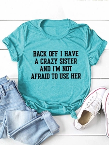 Flat lay of lake blue crew neck T-shirt with black slogan print on white wood background