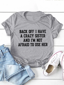Detail of grey crewneck T-shirt with slogan print and stylish knotted hem on wooden background