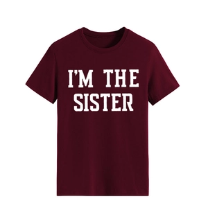 Gros plan du slogan blanc 'I'M THE SISTER' imprimé sur un T-shirt en coton bordeaux