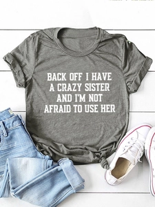 Flat lay of a grey crewneck t-shirt with white slogan print on a white wood background