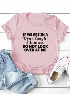 Detailed flat lay of a light pink t-shirt with black letter print on white wood background