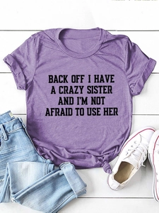 Flat lay of purple crewneck T-shirt with humorous slogan and denim jeans on wood background