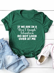 Flat lay of dark green cotton T-shirt with white slogan print on white wood background