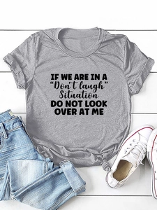Detailed view of dark grey knotted t-shirt with black letter print on wooden floor
