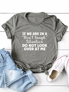 Flat lay of gray crew neck T-shirt with white humor slogan text and denim jeans