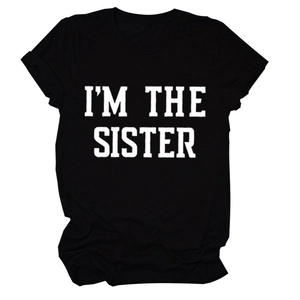 Gros plan sur l'imprimé I'M THE SISTER sur un t-shirt noir à manches courtes en coton