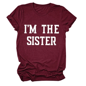 Gros plan du slogan blanc I'M THE SISTER sur le tissu d'un t-shirt bordeaux