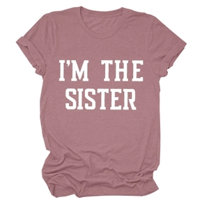 Détail du lettrage blanc I'M THE SISTER sur un t-shirt en coton rose poudré doux