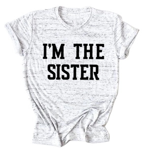 Gros plan du tissu gris chiné avec inscription I'M THE SISTER en gras sur le t-shirt