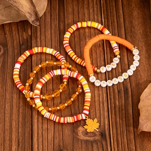 Handmade autumn bracelet set with maple leaf charm and beads on wood background