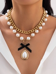 Close-up of multi-layer pearl necklace featuring a black bow and teardrop pearl pendant