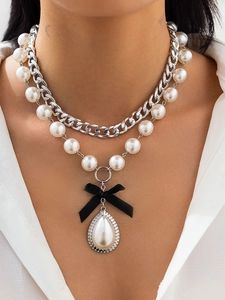 Close-up of layered pearl necklace with black silk bow and teardrop pearl pendant