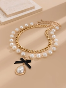 Detail of double-layered pearl necklace with black ribbon bow and gold teardrop pendant
