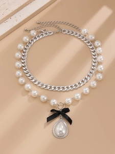 Detail of layered pearl necklace with black bow and teardrop pearl pendant with zircon
