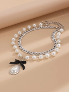 Detail of silver chain and pearl necklace with a black ribbon and teardrop pearl pendant