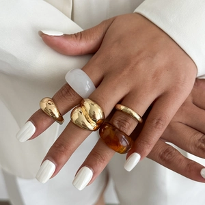 Minimalistische stapelbare gouden en hars ringen getoond op de hand van een model