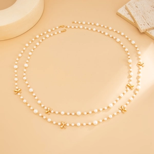 Close-up of double-layer long pearl necklace with golden metal bowknot charms and clasp