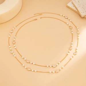 Detailed view of long gold chain necklace with white pearls and round crystal beads