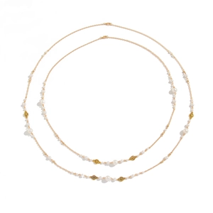 Long gold necklace with white pearls and hollow flower charms on a white background