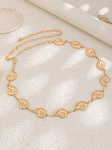 Detail of gold seashell body chain with nautilus charms on beach sand background