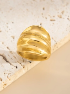 Vue macro d'une bague dorée ondulée irrégulière présentée sur une pierre naturelle