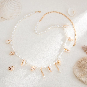 Detailed close-up of starfish shell pendants and imitation pearls on a summer body chain