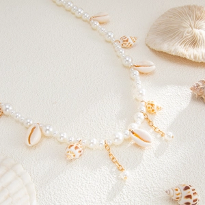 Close-up of pearl beaded body chain with natural seashell and starfish charms in ocean style