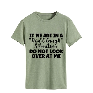 Detail of sage green cotton t-shirt showing black artistic slogan and fabric texture
