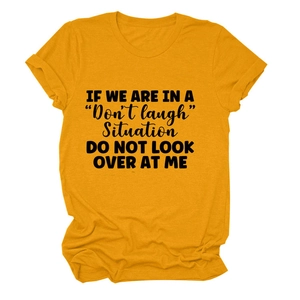 Close-up of the slogan print and folded sleeve detail on ginger yellow cotton t-shirt