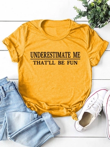 Flachbild von gelbem T-Shirt mit 'UNDERESTIMATE ME' Aufdruck, Jeans und weißen Turnschuhen