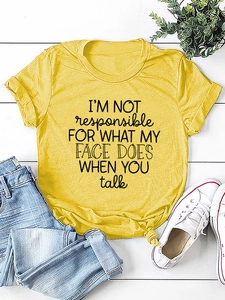 Flat lay of yellow t-shirt with side knot detail and graphic quote print on wood background
