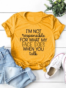 Detail of mustard yellow t-shirt with slogan print paired with light blue jeans