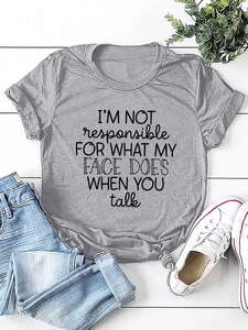 Flat lay of gray cotton t-shirt with slogan print and knotted hem on white wood